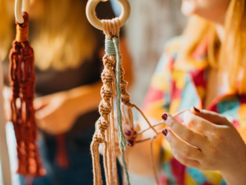 Hands making knots in a macramé class.